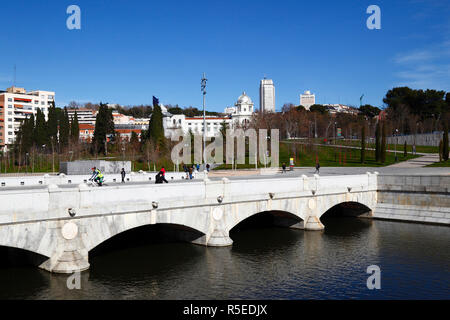 Radfahrer überqueren die Brücke Puente del Rey über den Fluss Manzanares und die Jardines del Virgen del Puerto, vom Park Casa de Campo aus gesehen, Madrid, Spanien Stockfoto