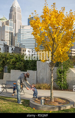 CHARLOTTE, NC - November 25, 2016: ein Vater spielt mit seinem jungen Sohn in Romare Bearden Park in Uptown Charlotte, North Carolina. Stockfoto