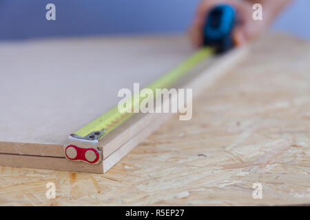 Nahaufnahme eines Menschen Hand messen Holz mit einem Band. Heimwerker. Messung. Foto Stockfoto
