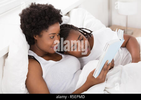 Mutter und Kind ein Buch lesen im Bett Stockfoto