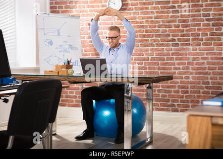 Happy Geschäftsmann Entspannen auf Fitness Ball im Büro Stockfoto