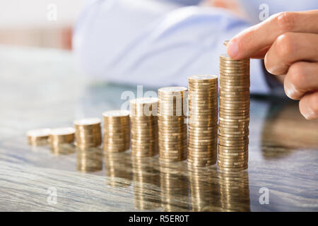 Person, Münze über die Münzen Stapel Stockfoto