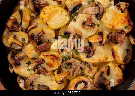 Eine Nahaufnahme von gekochtem Gemüse, Kartoffeln, Erbsen, Champignons, in der Pfanne, von oben, warmen Herbst essen Textur Schuß Stockfoto