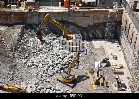 New York City, New York, USA: Arbeiter zusehen, wie Maschinen, Pausen Manhattan schiefer Gestein als Baumaterial auf einem Gebäude in Midtown Manhattan beginnt. Stockfoto