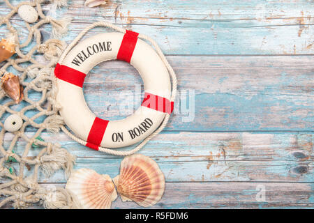 Nautica Hintergrund mit Sicherheit Boje mit dem Text Willkommen an Board, Muscheln und Fischen net auf einem blauen Hintergrund Gerüst aus Holz Stockfoto