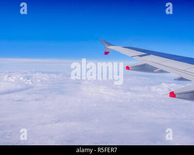 Blick aus dem Flugzeug Fenster: ein Flugzeug Flügel über Wolken und blauer Himmel Stockfoto