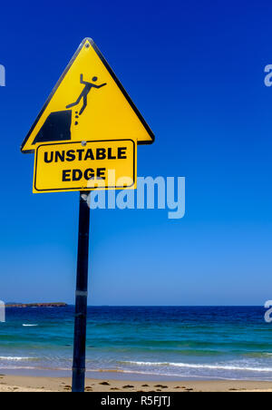 Instabile edge Zeichen mit Blick auf Meer, Person fallen aus Felsen, Australische Schilder Stockfoto