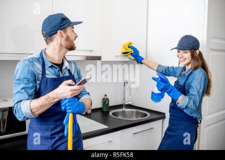 Mann und Frau als eine professionelle Reinigung in uniiform Spaß während der Arbeit in der Küche Stockfoto