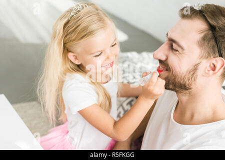 Adorable kleine Tochter Anwendung Make-up zu den glücklichen Vater zu Hause Stockfoto