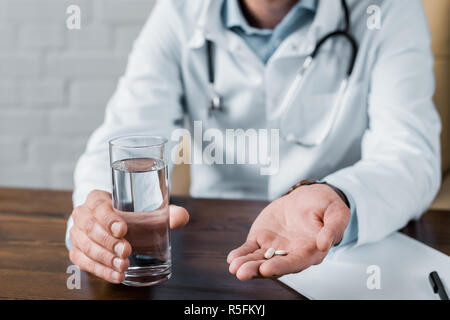 7/8 Schuß von Arzt, Pillen und Wasser zu Patienten im Büro Stockfoto