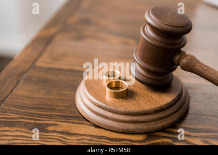 Nahaufnahme der Richter Hammer und Trauringe auf Holztisch, Scheidung Konzept Stockfoto