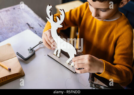 Junge macht Holz- Hirsche Figur Stockfoto