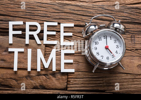 Freie Zeit Text von Wecker auf hölzernen Tisch Stockfoto
