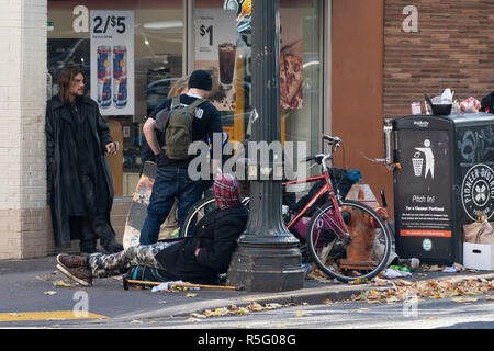 Portland, OR/USA, 17. November 2018: Obdachlose sitzen außerhalb des Convenience Store neben dem Mülleimer. Stockfoto