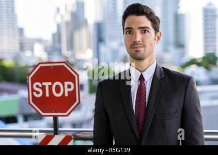 Portrait der junge Geschäftsmann neben STOP-Schild Stockfoto