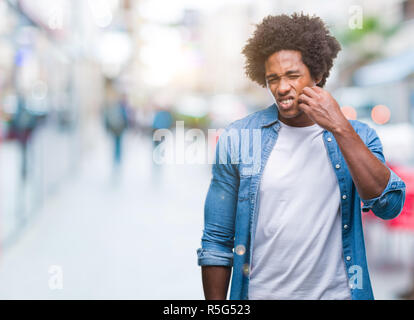 Afro-amerikanische Mann über isolierte Hintergrund berühren den Mund mit der Hand mit schmerzhaften Ausdruck wegen Zahnschmerzen oder zahnmedizinische Krankheit auf die Zähne. Zahnarzt c Stockfoto