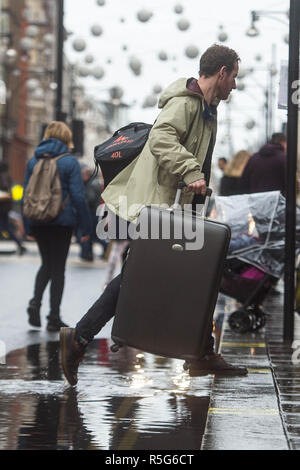 Ein Mann Fortschritte über eine Pfütze auf der Oxford Street in London während der nassen Wetter. Stockfoto