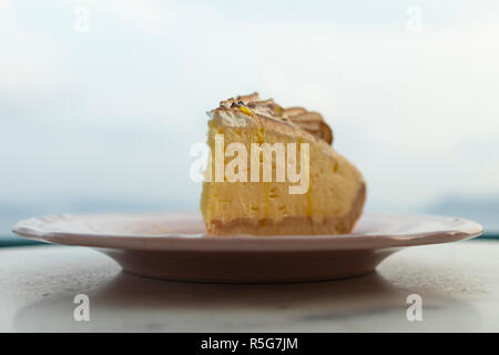 Nahaufnahme einer Zitrone Kuchen auf eine Platte, mit dunstigen Himmel im Hintergrund, Seitenansicht. Oia, Santorini, Griechenland. Stockfoto