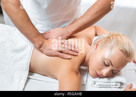Männlichen Masseur, Rückenmassage, attraktive Frau in Spa. Stockfoto