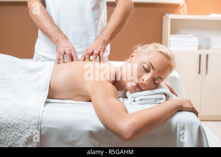 Blonde Frau liegend, mit geschlossenen Augen, während Mann, Massage Stockfoto
