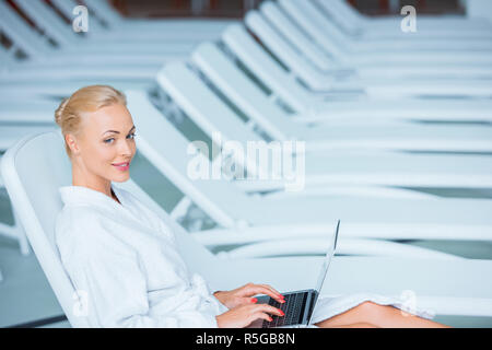 Schöne Frau mit Laptop im Bademantel Stockfoto