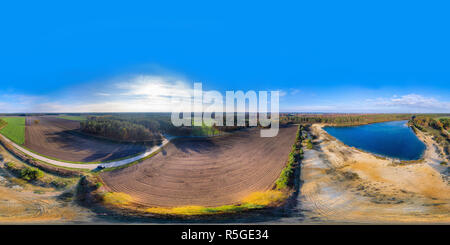 360 Grad Panorama Ansicht von 360 Grad Panorama von einem Feld und einem Kies Teich neben einem Wald und einem Land Straße, mit der Drohne in der Flucht