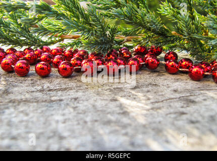 Rote Perlen und Zweige von Nadelgehölzen auf einem Hintergrund von rustikalen, mit Holz mit Schnee im sonnigen Tag. Platz zu kopieren, Text, deine Worte. Horizontale Stockfoto