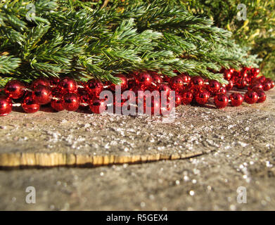 Rote Perlen und Zweige von Nadelgehölzen auf einem Hintergrund von rustikalen, mit Holz mit Schnee im sonnigen Tag. Platz zu kopieren, Text, deine Worte. Horizontale Stockfoto