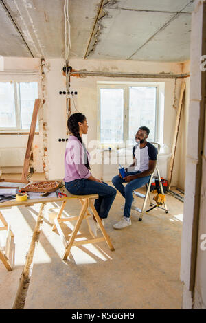Glückliches junges Paar essen Pizza und die Renovierung von Home Stockfoto