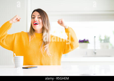 Junge schöne Frau trinkt eine Tasse Kaffee zu Hause Übersicht arme Muskeln lächelte stolz. Fitness Concept. Stockfoto