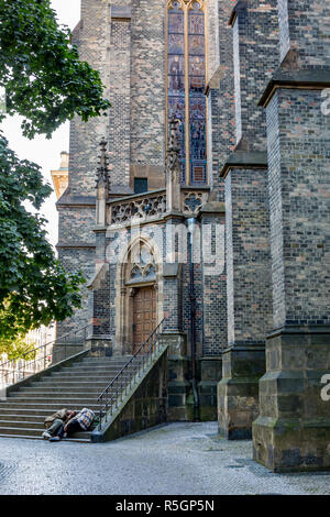 Zwei unkenntlich obdachlose Männer schlafen in die Schatten auf den unteren Stufen der Treppe der Gotischen Kathedrale in der Altstadt von Prag, Tschechische Republik Stockfoto