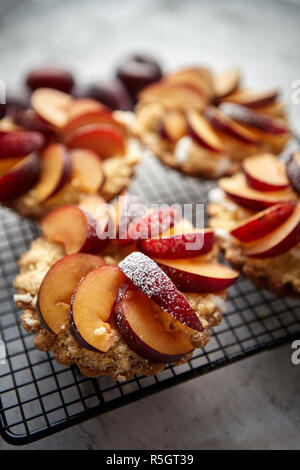 Hausgemachte Torten mit frischen Pflaumen Schichten auf Eisen backen Grill platziert bröckeln Stockfoto