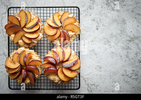 Hausgemachte Torten mit frischen Pflaumen Schichten auf Eisen backen Grill platziert bröckeln Stockfoto