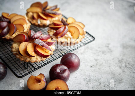 Hausgemachte Torten mit frischen Pflaumen Schichten auf Eisen backen Grill platziert bröckeln Stockfoto