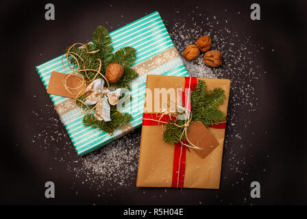 Bunte und dekoriert, Weihnachten Geschenke auf schwarzen Hintergrund mit etwas Schnee Flocken Stockfoto