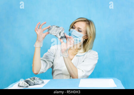 Eine Frau lab Arbeiter untersucht die Steine mit einer Pinzette nimmt die Fasern von schädlichen Asbest. Stockfoto