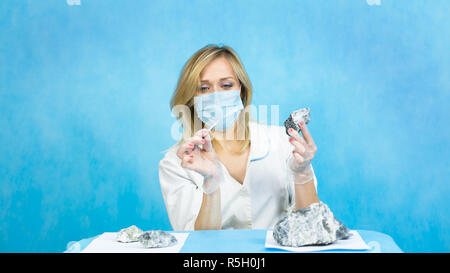 Eine Frau lab Arbeiter untersucht die Steine mit einer Pinzette nimmt die Fasern von schädlichen Asbest. Stockfoto