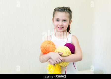 Das kleine Mädchen hält stricken Garne in den Händen, und die Garne hängt an den Kopf. Stockfoto