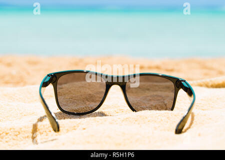 Schwarze Sonnenbrille auf Sand Stockfoto