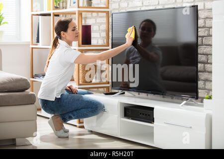 Frau Abwischen der TV-Bildschirm zu Hause Stockfoto