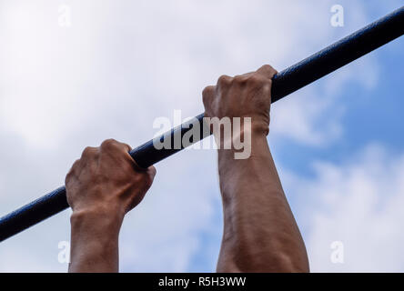 Hände auf die Bar zu schließen. Der Mann zieht sich an der Bar. Sport an der frischen Luft. Horizontale Leiste. Stockfoto