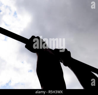 Silhouette der Hände in einer horizontalen Leiste. Hände auf die Bar zu schließen. Der Mann zieht sich an der Bar. Sport an der frischen Luft. Horizontale Leiste. Stockfoto