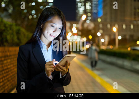 Geschäftsfrau Arbeiten am Handy in Straße bei Nacht Stockfoto