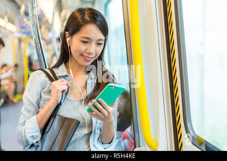 Frau hören Song am Telefon und mit dem Zug in Hongkong Stockfoto