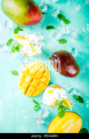 Tropische süßes Dessert Getränke. mango Milchshake oder Smoothie Cocktail, mit Mango Slices, Minze und Eiswürfel, hellblauer Hintergrund Kopie Raum Stockfoto
