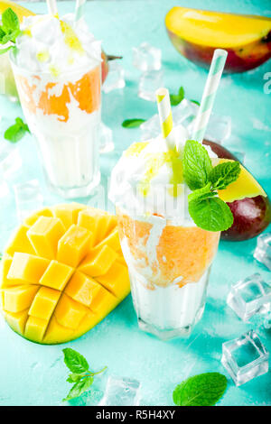 Tropische süßes Dessert Getränke. mango Milchshake oder Smoothie Cocktail, mit Mango Slices, Minze und Eiswürfel, hellblauer Hintergrund Kopie Raum Stockfoto