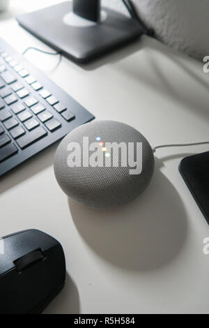 Grau Google Home Mini-Gerät auf einem weißen Schreibtisch Stockfoto