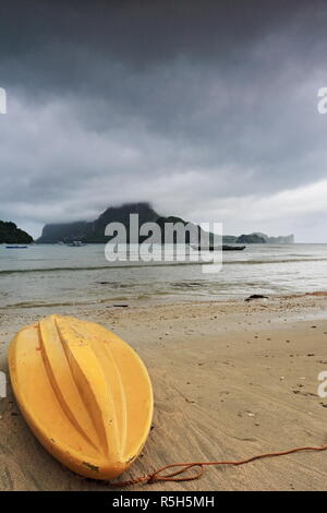 Gelbe fiberglas Kajak kopfüber am Strand gestrandet - gehen in einem verregneten Morgen festgemacht, die sie daran hindern, Meer zum Fischen und zu Stockfoto