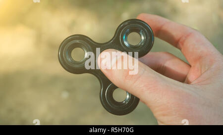 Das Spiel mit den schwarzen zappeln Spinner. Spielzeug-Spinner in der hand. Sonne-Effekt Stockfoto