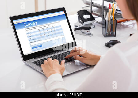 Geschäftsfrau Füllung Umfrage auf Laptop Stockfoto